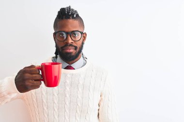 Saçları örgülü Afrikalı Amerikalı bir adam izole edilmiş beyaz arka planda bir fincan kahve içiyor. Akıllı bir yüz ifadesi var ve ciddi düşünüyor.