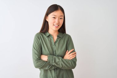 İzole edilmiş beyaz arka planda duran yeşil tişörtlü genç Çinli kadın kameraya bakarken kollarını kavuşturup gülümsüyor. Pozitif kişi.