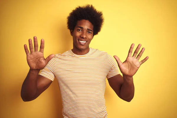 自信と幸せ笑顔ながら 指の番号10で示すと指摘独立した黄色の背景の上に立って縞模様のTシャツを着てアフロ髪を持つアメリカ人男性 — ストック写真