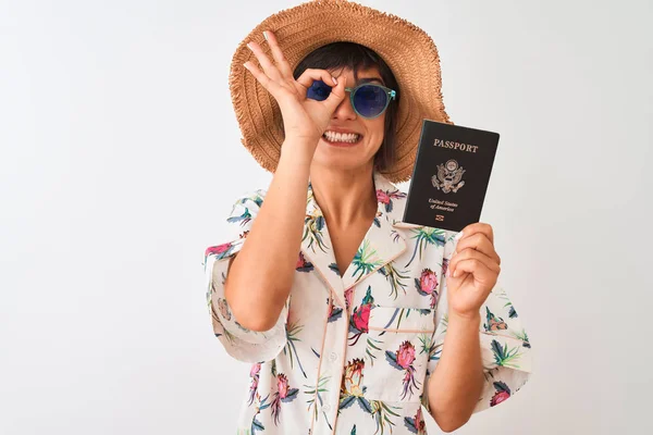 Tourist woman on vacation holding USA United States passport over isolated white background with happy face smiling doing ok sign with hand on eye looking through fingers