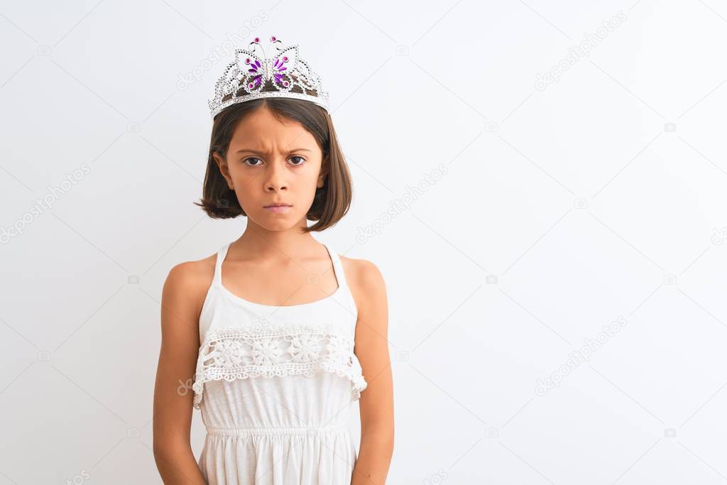 Beautiful child girl wearing princess crown standing over isolated white background skeptic and nervous, frowning upset because of problem. Negative person.