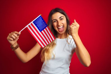 Amerika Birleşik Devletleri bayrağını kırmızı arka planda tutan genç bir kadın gururla bağırıyor ve zaferi ve başarıyı kutluyor. Çok heyecanlı, coşkulu bir duygu.