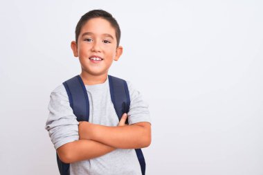 Güzel öğrenci çocuk sırt çantası takıyor. İzole edilmiş beyaz arka plan üzerinde duruyor. Kollarını kavuşturup kameraya bakarken gülümsüyor. Pozitif kişi.