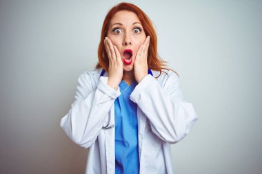 Genç kızıl saçlı kadın steteskop kullanıyor. İzole edilmiş beyaz arka plan üzerinde. Korkmuş ve şok olmuş.
