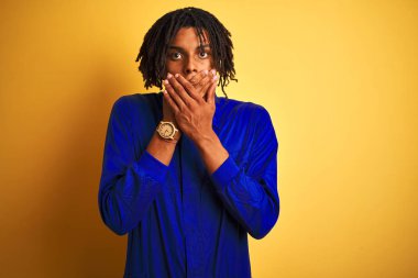 Sarı arka plan üzerinde mekanik üniforma giyen Afrikalı işçi ağzını yanlışlıkla ellerle kapatarak şok etti. Gizli konsept.