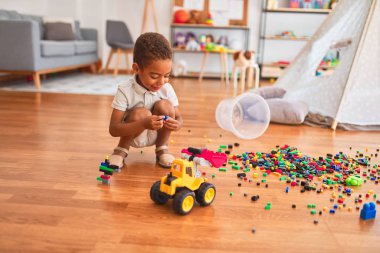 Güzel Afrikalı Amerikalı çocuk anaokulunda gülümseyen küçük yapı taşlarıyla oynuyor.