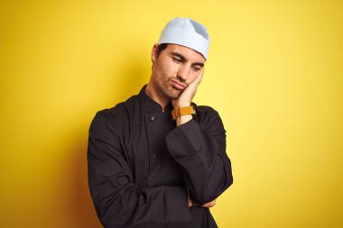 Üniformalı ve şapkalı genç aşçı kolları çaprazlanmış depresyondan sıkılmış ve yorgun görünüyor..