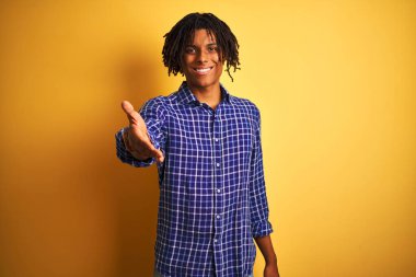 Rastgele tişörtlü Afro bir adam izole edilmiş sarı arka planda durup dostça gülümseyerek selamlama ve hoş geldin diyor. Başarılı bir iş..