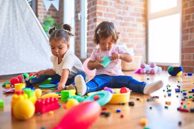 Anaokulunda plastik yemek ve çatal bıçak kullanarak yemek oynayan sevimli bebekler.