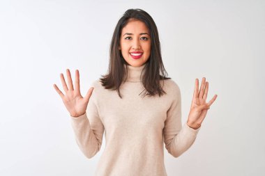 Balıkçı yaka kazak giyen güzel Çinli kadın izole edilmiş beyaz arka planda dikiliyor ve dokuz numarayı gösterirken kendine güvenen ve mutlu bir şekilde gülümsüyor..