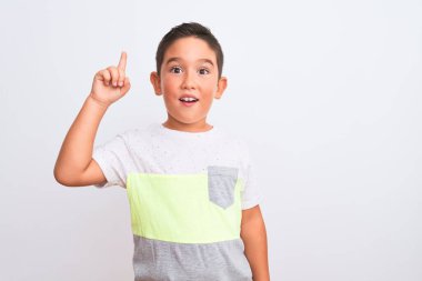 İzole edilmiş beyaz arka planda duran günlük tişörtler giyen güzel çocuk başarılı bir fikri işaret ediyor. Heyecanlı ve mutlu. Bir numara..
