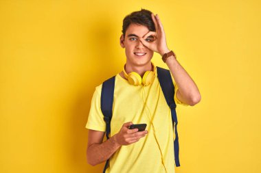 Kulaklık takan genç bir çocuk ve izole edilmiş arka planda akıllı telefon kullanıyor. Gülümseyen bir yüzü var. Tamam.