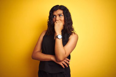 Transsexual transgender elegant businesswoman standing over isolated yellow background looking stressed and nervous with hands on mouth biting nails. Anxiety problem.