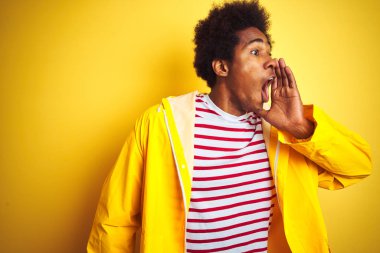 Siyah saçlı Afro-Amerikalı bir adam izole edilmiş sarı arka planda durmuş el ele tutuşarak bağırıyor ve bağırıyordu. İletişim konsepti.