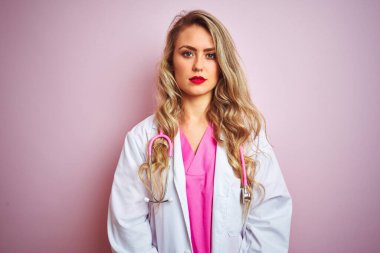 Pembe izole arka plan üzerinde steteskop kullanan güzel bir kadın. Yüzünde ciddi bir ifadeyle rahatlamış. Basit ve doğal bir şekilde kameraya bakıyorsun..
