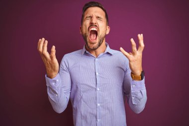 Mor izole edilmiş arka plan üzerinde zarif gömlekler giyen genç iş adamı kollarını kaldırmış ve gözleri kapalı heyecanla haykırarak başarının çılgınlığını kutluyor. Kazanan konsept