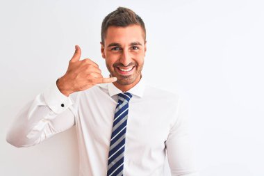 Genç, yakışıklı, zarif iş adamı izole edilmiş arka planda gülümseyen, el ve parmaklarıyla telefon hareketi yapan telefonda konuşur gibi. İletişim kavramları.