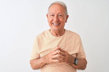 İzole edilmiş beyaz arka planda duran çizgili tişört giyen yaşlı gri saçlı adam ellerini birleştirip gülümseyerek rahat ve neşeli görünmesini diliyordu. Başarı ve iyimser