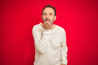 Yakışıklı, orta yaşlı, gri saçlı, izole edilmiş kırmızı arka planı olan yakışıklı bir adam. Kameraya bakıp havada öpücükler savuruyor. Güzel ve seksi. Aşk ifadesi.