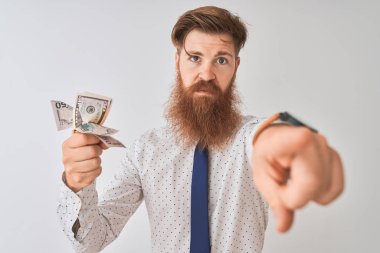 Kamera ve size, el işareti, ön emin jest parmak ile işaret izole beyaz arka planda duran genç Redhead İrlandalı işadamı dolar tutarak
