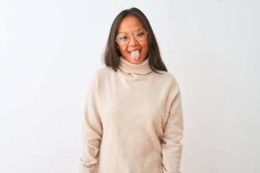 Balıkçı yaka kazak ve gözlük takan genç Çinli bir kadın izole edilmiş beyaz arka planda mutlu bir ifadeyle dilini dışarı çıkarıyor. Duygu kavramı.