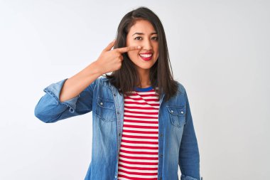 İzole edilmiş beyaz arka plan üzerinde çizgili t-shirt ve kot gömlek giyen genç Çinli bir kadın. Parmak parmağa, burun yüze, neşeli bir şekilde gülümsüyor. Güzellik konsepti