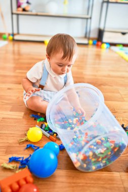 Anaokulunda bir sürü oyuncakla oynayan sevimli bir çocuk.