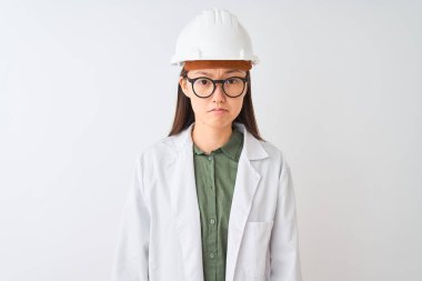 Genç Çinli mühendis kadın, izole edilmiş beyaz arka planda ceket kaskı gözlüğü takıyor ve üzgün, sinirli ve korkmuş bir şekilde endişe ediyor. Üzücü ifade.