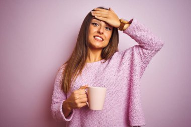 İzole edilmiş pembe arka planda duran bir fincan kahve içen genç ve güzel bir kadın. Elleri başının üstünde, utanç ve şaşkınlık dolu, sinirli ve hayal kırıklığına uğramış bir şekilde. Hata için korku ve üzüntü.