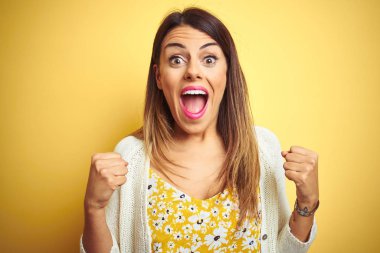 Sarı arka plan üzerinde duran genç ve güzel bir kadın kollarını kaldırarak ve açık gözlerle başarıyı kutluyor. Kazanan konsept.