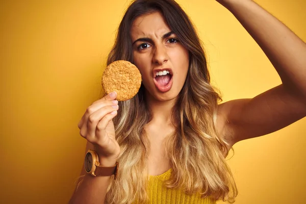 Jovem Mulher Bonita Comer Biscoito Sobre Fundo Isolado Cinza Irritado — Fotografia de Stock