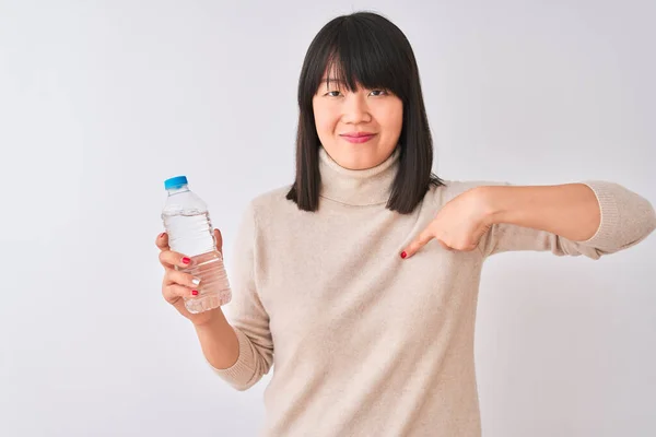 年轻美丽的中国女人 在与世隔绝的白色背景上端着一瓶水 满脸诧异地指着自己 — 图库照片