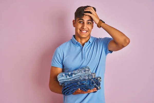 Young Indian Shopkeeper Man Holding Folded Jeans Standing Isolated Pink — ストック写真