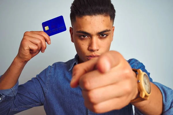 年轻的巴西顾客持着信用卡站在孤立的白色背景之上 用手指指向相机和你 正面做出积极而自信的手势 — 图库照片