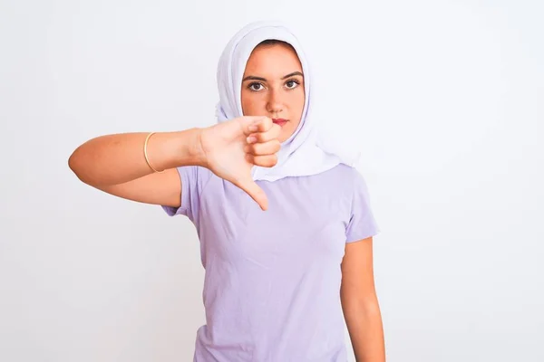 孤立した白い背景の上に立っているヒジャーブを身に着けている若い美しいアラビア人の少女は 親指を下にジェスチャーで拒絶と否定を示す不満と怒りを見ています 悪い表現 — ストック写真