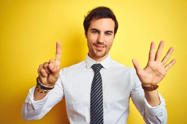 年轻英俊的生意人 身穿雅致的衬衫 打着孤立的黄色背景的领带 带着自信而快乐的微笑 用手指指了指六号 — 图库照片