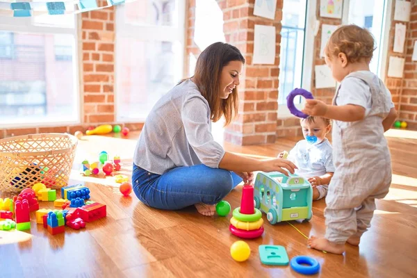 Hermosa Maestra Niños Pequeños Jugando Alrededor Montón Juguetes Jardín Infantes —  Fotos de Stock