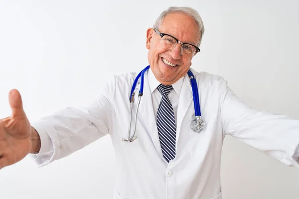 孤立した白い背景の上に立って聴診器を身に着けているシニア白髪の医者の男は抱擁のために開いた腕で笑顔カメラを見て 幸せを受け入れる陽気な表情 — ストック写真