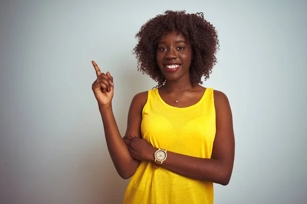 年轻的非洲黑人妇女穿着黄色的T恤 披着孤立的白色背景 脸上挂着大大的笑容 手指手画脚地看着摄像机的侧面 — 图库照片