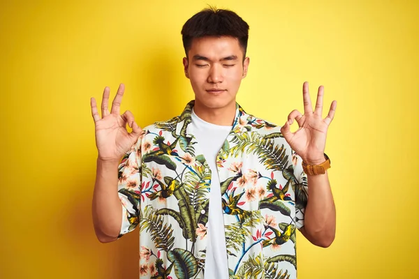 孤立した黄色の背景の上に夏のシャツを着て休暇中のアジアの中国人男性はリラックスし 目を閉じて指で瞑想のジェスチャーをして笑顔 ヨガのコンセプト — ストック写真