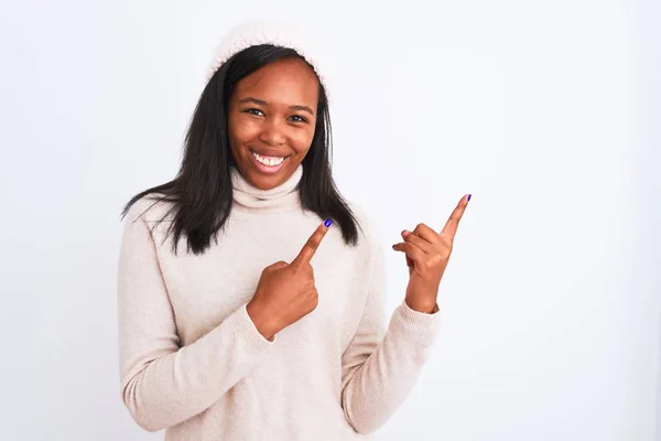 美しい若いアフリカ系アメリカ人の女性は タートルネックセーターと冬の帽子を身に着けています笑顔とカメラを見て2本の手と指で側面を指して — ストック写真