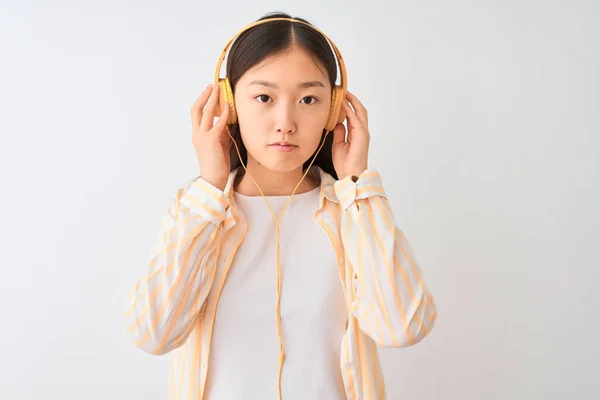 若い中国人女性の音楽を聴いてヘッドフォンで隔離された白い背景と自信を持って表現上のスマート顔の思考深刻な — ストック写真