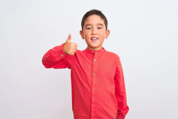 孤立した白い背景の上に立つエレガントな赤いシャツを着た美しい少年は 手で幸せな親指を立ててジェスチャーをします 成功を示すカメラを見て表現を承認する — ストック写真