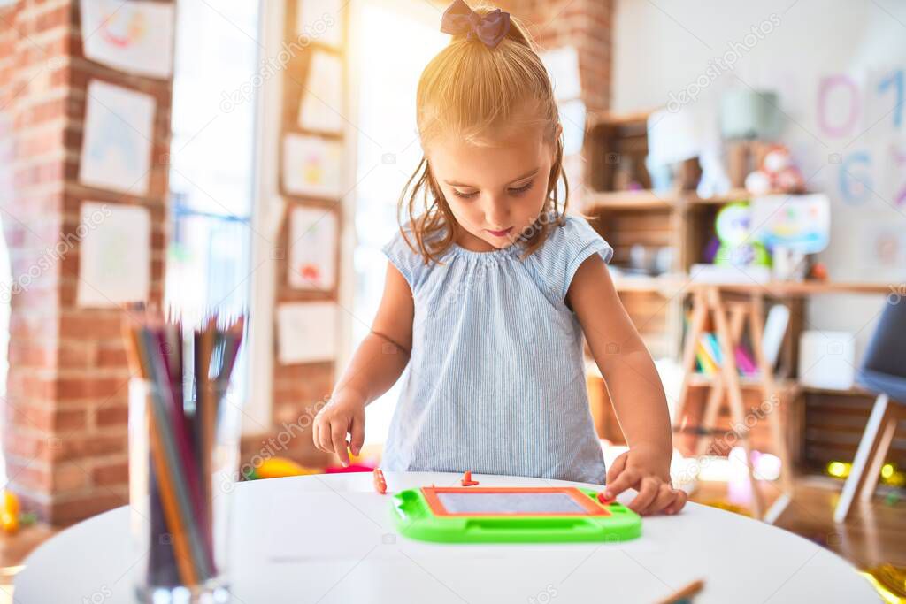 Young beautiful blonde girl kid enjoying play school with toys at kindergarten, smiling happy painting with pencil colors at home