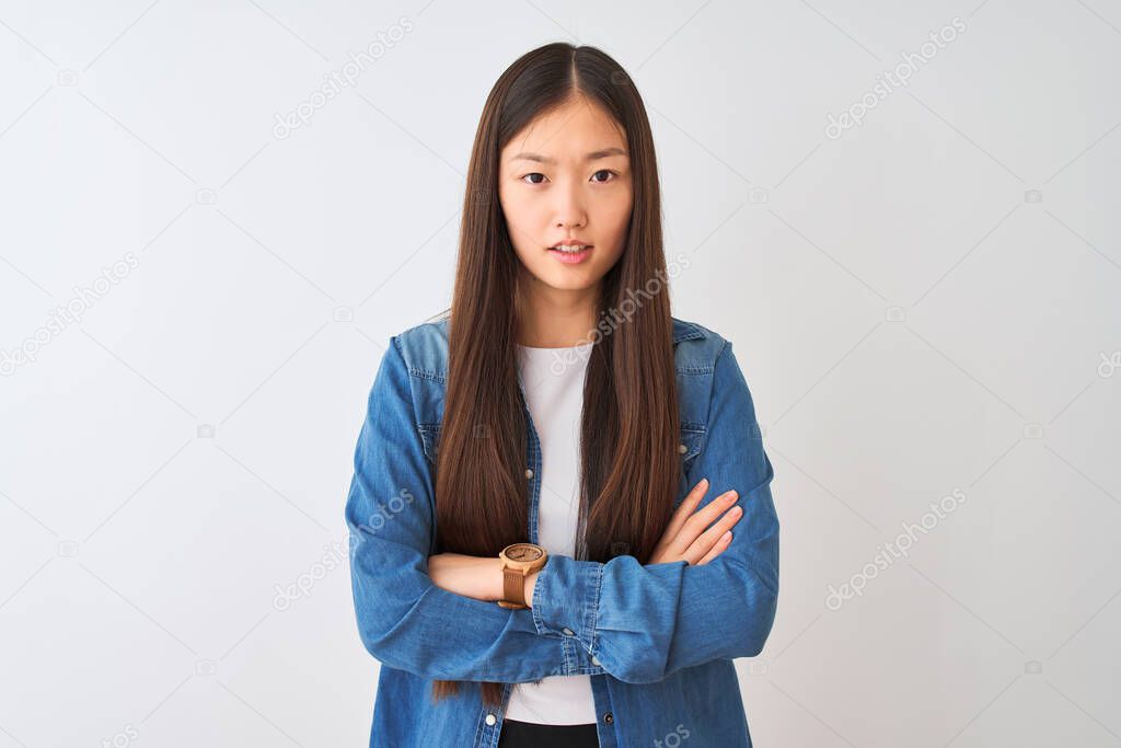Young chinese woman wearing denim shirt standing over isolated white background skeptic and nervous, disapproving expression on face with crossed arms. Negative person.