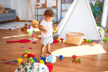 Anaokulunda bir sürü oyuncağın etrafına taş döşeyen sevimli bir çocuk.