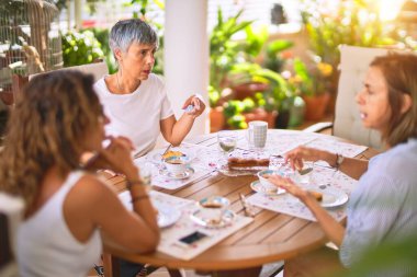 Genç ve güzel bir kız mutlu ve kendinden emin bir şekilde terasta oturmuş bir fincan kahve içiyor.