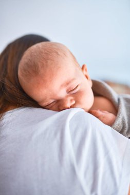 Genç, güzel bir kadın ve bebeği evde yerde duruyor. Anne kucağına aldı ve oğlunu kucakladı.