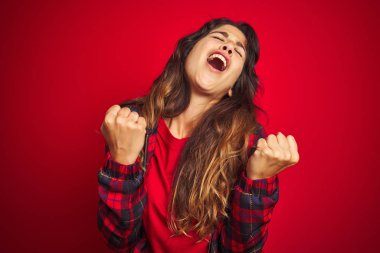 Genç ve güzel bir kadın, kırmızı izole edilmiş arka planda dikilirken kollarını kavuşturarak depresyondan sıkılmış ve yorgun görünüyor..