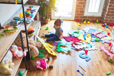 Anaokulunda yerde oturmuş oyuncaklarla oynayan güzel bir çocuk.